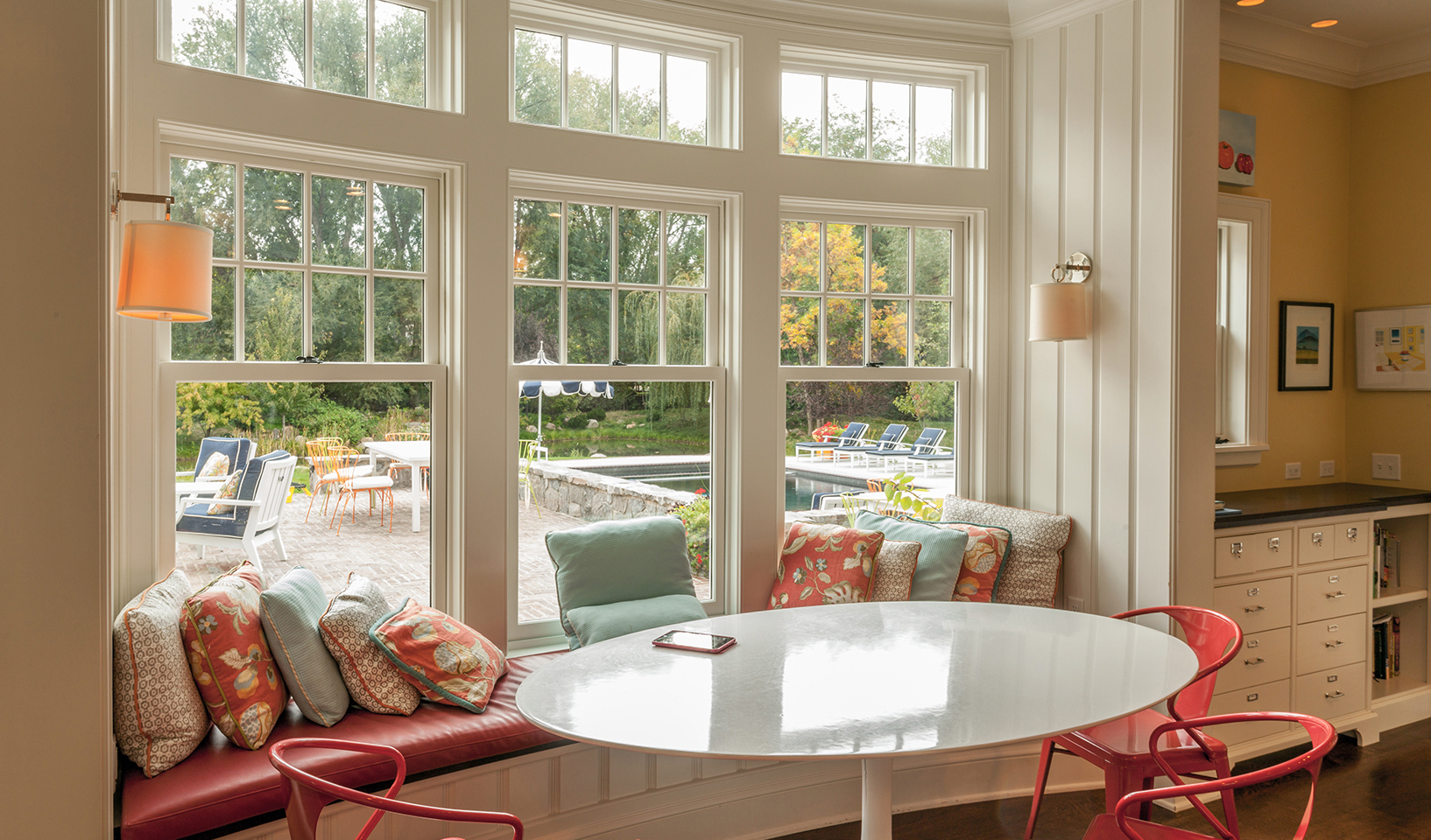 classical shingle style | interiors traditional | transitional kitchen | eating breakfast area nook | Cheerful floral | light | banquette | curved | window | seat | white | painted | vertical | paneling | upholstered | custom | round | pedestal | table | red | ES-LO Design Studio | San Francisco